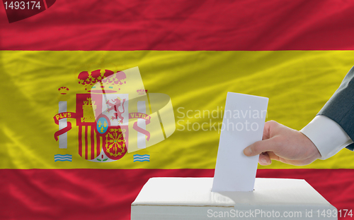 Image of man voting on elections in spain in front of flag