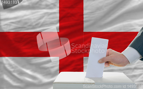 Image of man voting on elections in england in front of flag