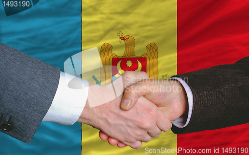 Image of businessmen handshake after good deal in front of moldova flag