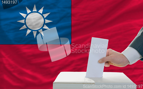 Image of man voting on elections in taiwan in front of flag