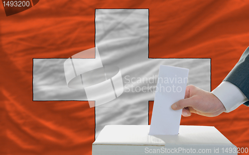 Image of man voting on elections in swiss in front of flag