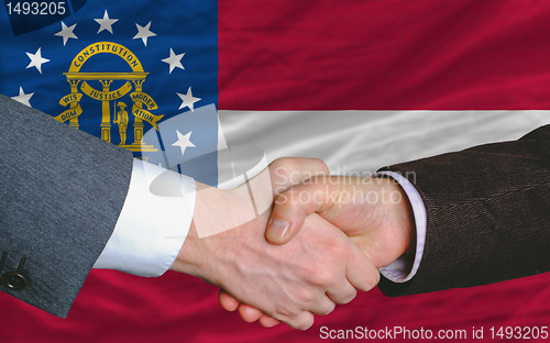 Image of businessmen handshake after good deal in front of georgia flag