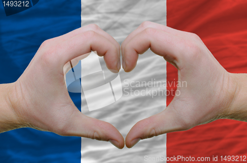 Image of Heart and love gesture showed by hands over flag of france backg