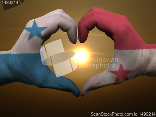 Image of Heart and love gesture by hands colored in panama flag during be