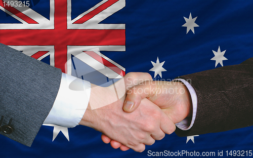 Image of businessmen handshake after good deal in front of australia flag