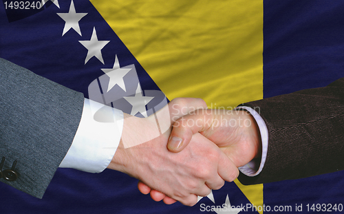 Image of businessmen handshake after good deal in front of bosnia herzego