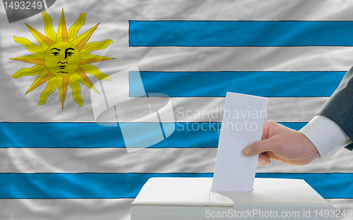 Image of man voting on elections in uruguay in front of flag