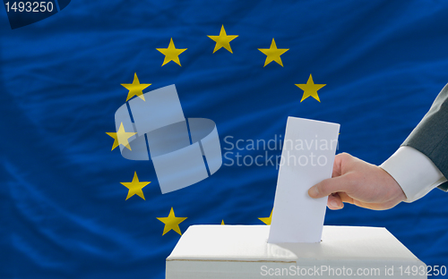 Image of man voting on elections in europe in front of flag