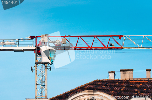 Image of Big industrial crane against blue sky building a house