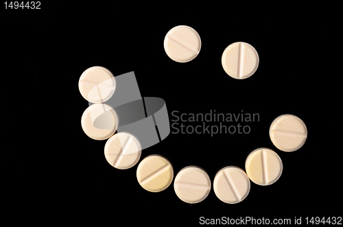 Image of Smiling face made out of pills on black background