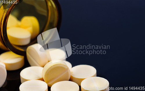 Image of Medical pills out of their bottle on black background