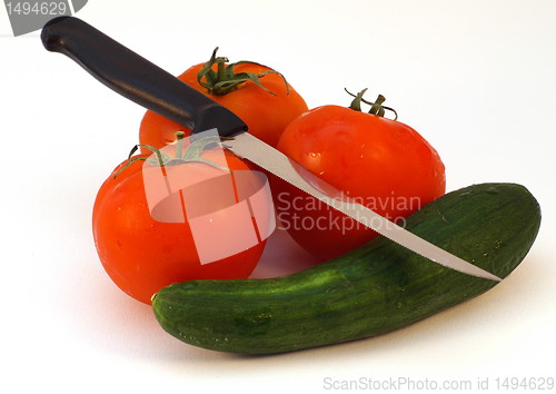 Image of A knife and fresh vegetables tomato and cucumber