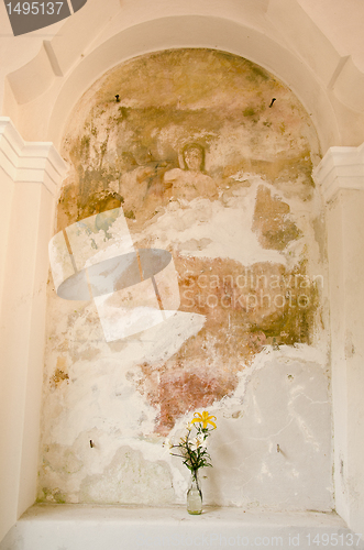 Image of Religious caple wall and vase with some flowers.