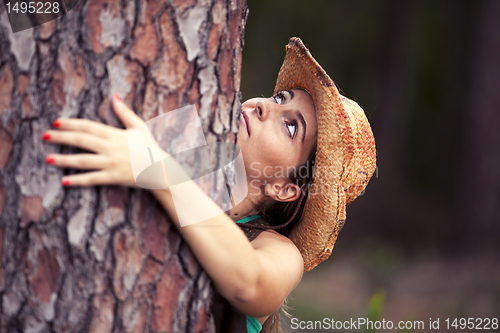 Image of Young woman embracing a tree