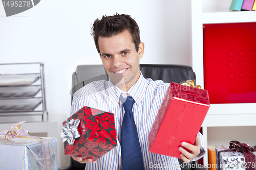 Image of Happy businessman giving christmas gifts