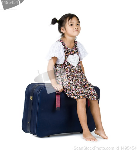 Image of cute girl sitting on luggage