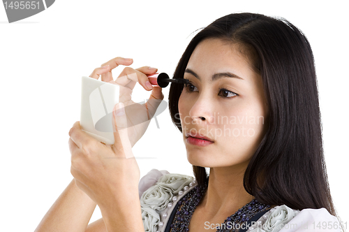 Image of young woman putting on black mascara 