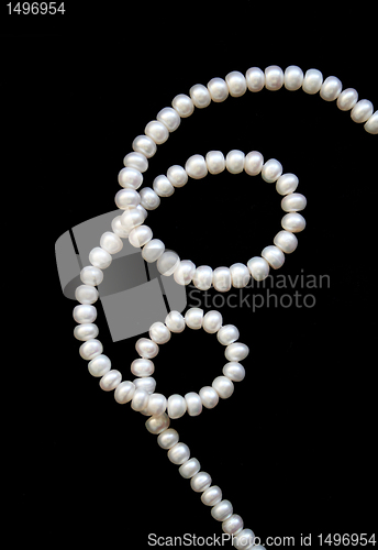 Image of White pearls on the black silk as background 