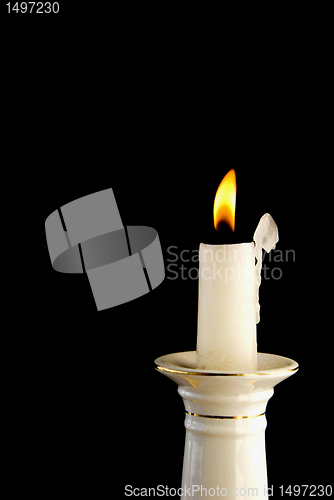 Image of White burning candle in candlestick 