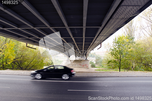 Image of Bridge underneath over river and  car going fast.