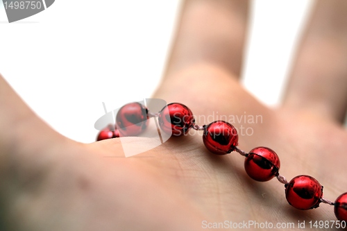 Image of hand with red pearls