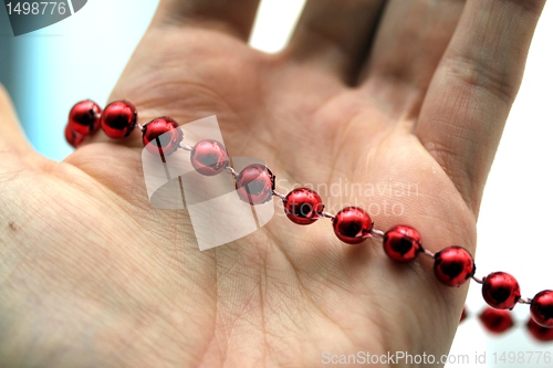 Image of hand with red pearls
