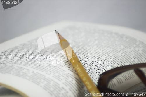 Image of Pencil and glasses on a book