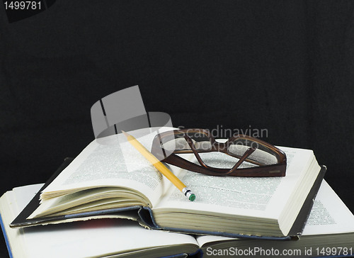 Image of Pencil and glasses on a book