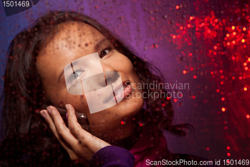 Image of Asian woman behind the glass in rainy weather calling