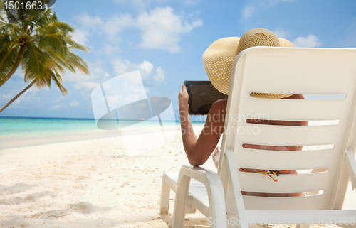 Image of Woman with tablet computer on the beach