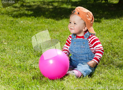 Image of Toddler sit with ball in the garden