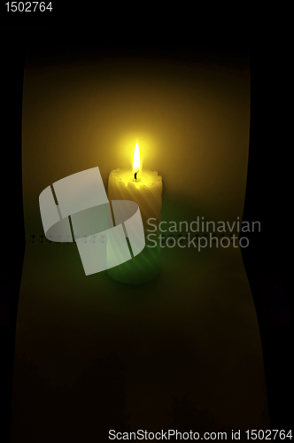 Image of a burning candle on the background of an open notebook