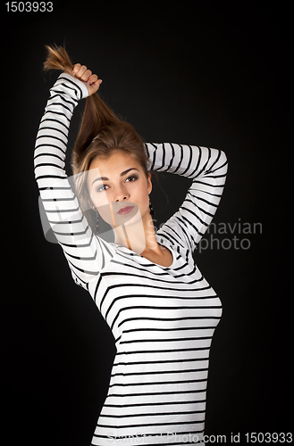 Image of Beautiful girl in a striped dress pulls his hair