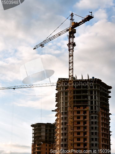 Image of Stand, house, construction crane in the sky with clouds