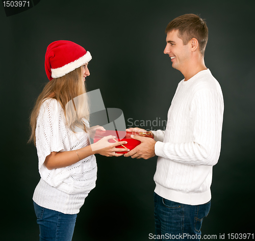 Image of The man gives the gift pregnant girl in Santa hat