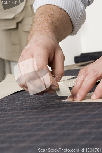 Image of detail of tailor's hand with chalk