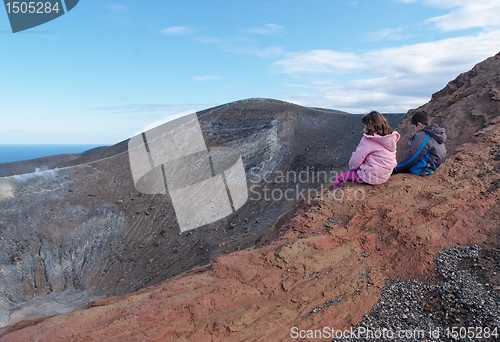 Image of Girl and boy sitting on the rim of volcano crater of Vulcano island near Sicily, Italy