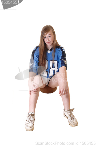 Image of Teenager girl sitting on football.