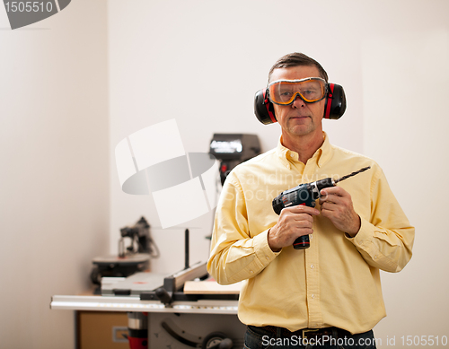 Image of Senior man holding power drill