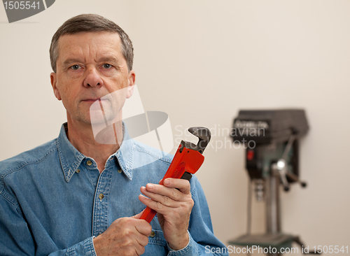 Image of Senior man holding a large wrench