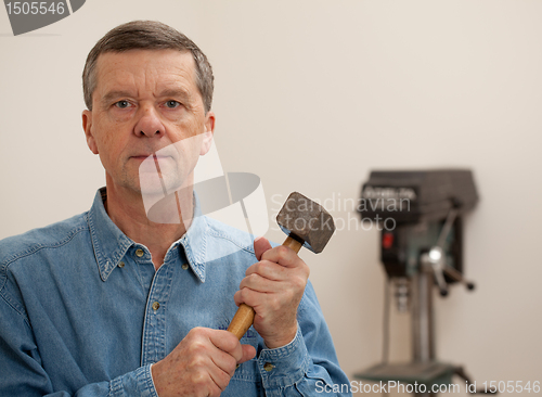 Image of Senior man holding a large hammer