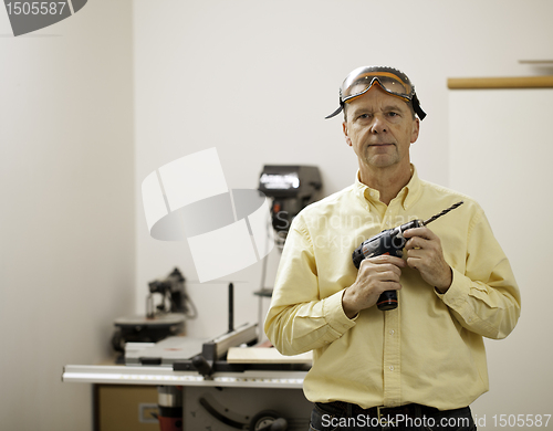 Image of Senior man holding power drill