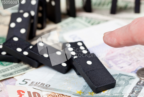 Image of Finger on dominoes on bank notes