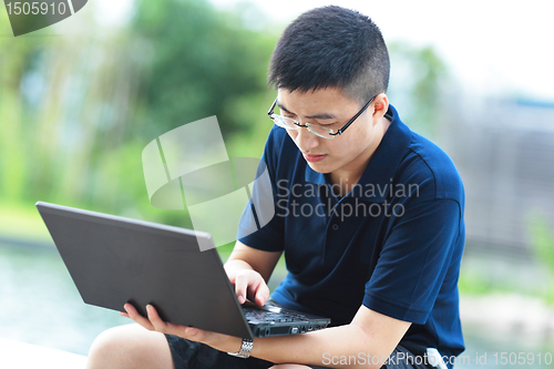 Image of Young man using laptop outdoor