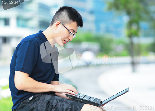 Image of Young man using laptop outdoor