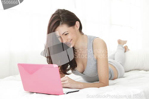 Image of Girl happy looking at her computer while in bed