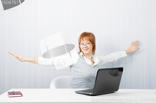 Image of girl with a laptop stretches in the workplace