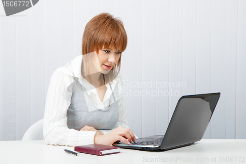 Image of Attractive girl with a laptop in the office