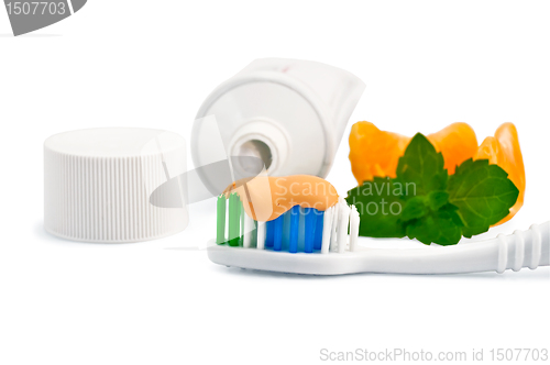 Image of Toothbrush with orange toothpaste and orange slices