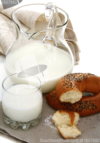 Image of Bagel with poppy seeds a pitcher of milk.